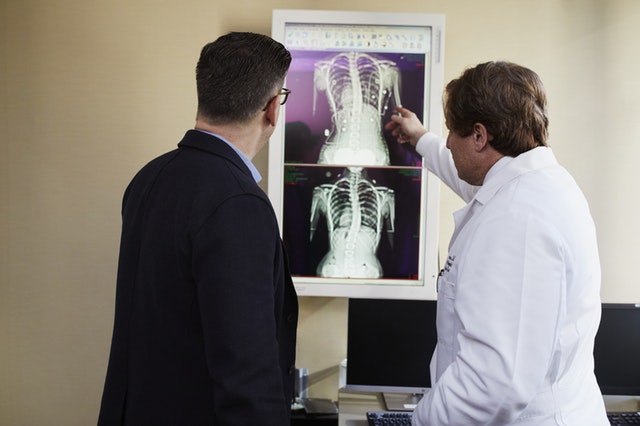 Doctor pointing x ray result beside man wearing black suit 2182972